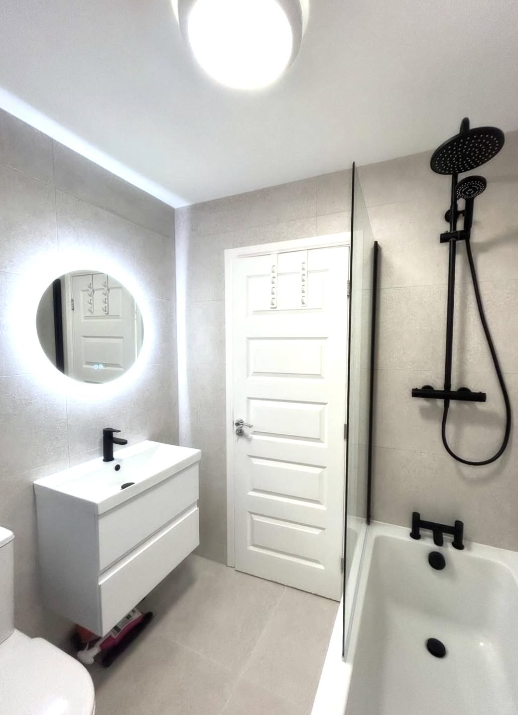 White bathroom installation with large format tiles and matt black brassware